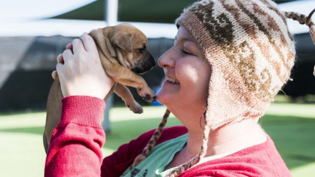 woman with cancer holding up a puppy